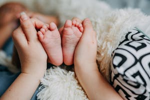 A close-up of gentle hands cradling tiny baby feet, exuding warmth and tenderness.