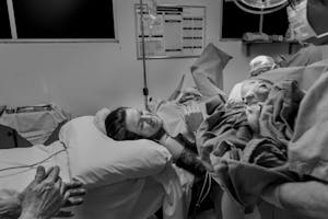 Black and white photo depicting a mother meeting her newborn in the delivery room.