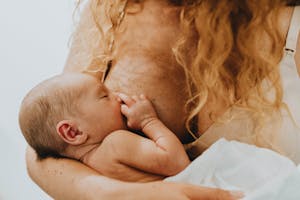 Close-up image of a mother lovingly breastfeeding her newborn, highlighting the bond and nurturing connection.